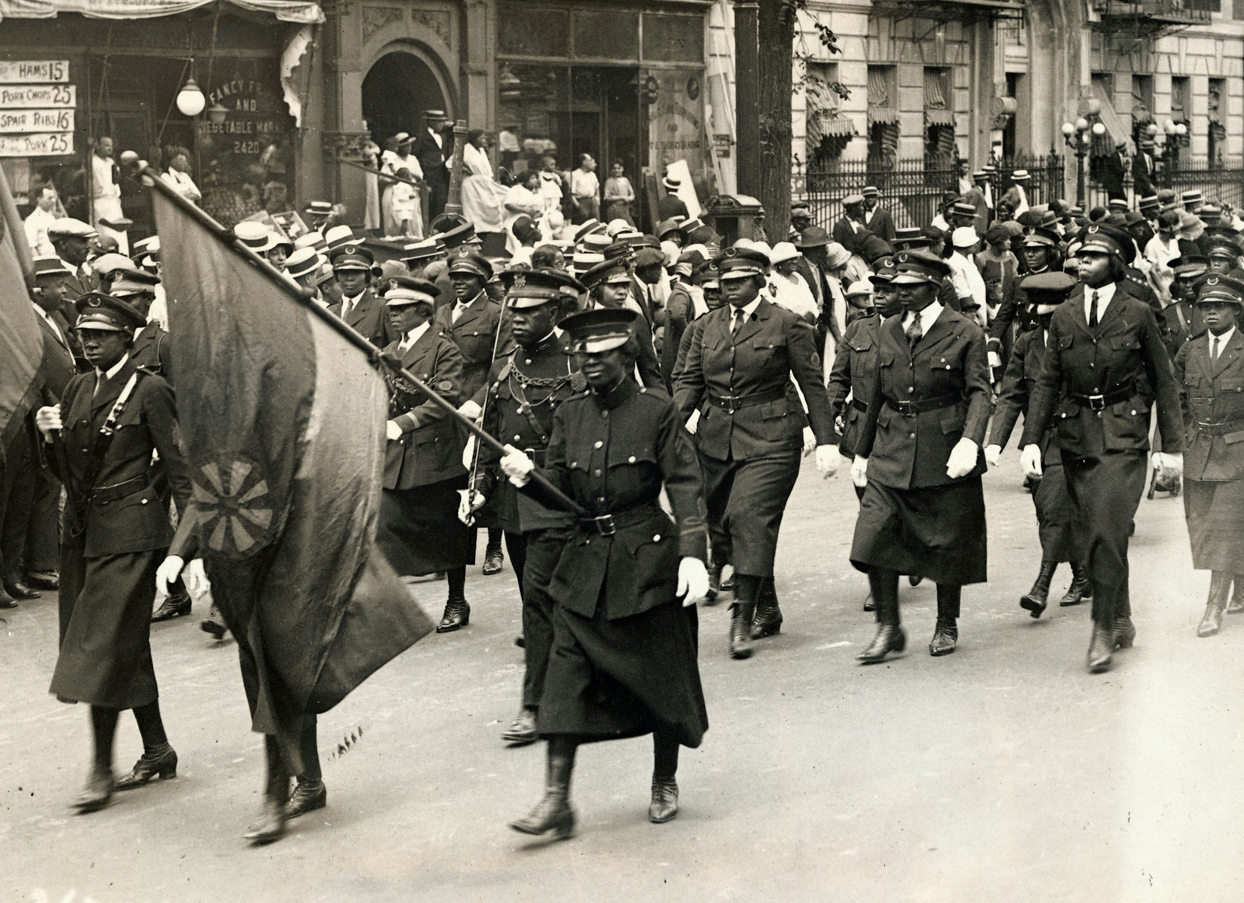 Uniformed attendees at a Marcus Garvey rally carry flags of the movement as they parade up Seventh Avenue in Harlem for a 1924 convention. Photo by George Rinhart/Corbis via Getty Images.